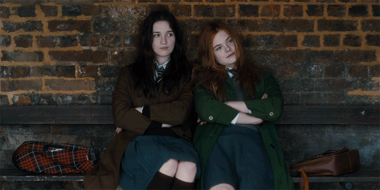 Girl friends sitting on bench blow air kisses at each other