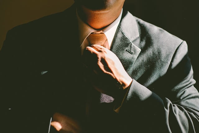 Man adjusts suit and tie