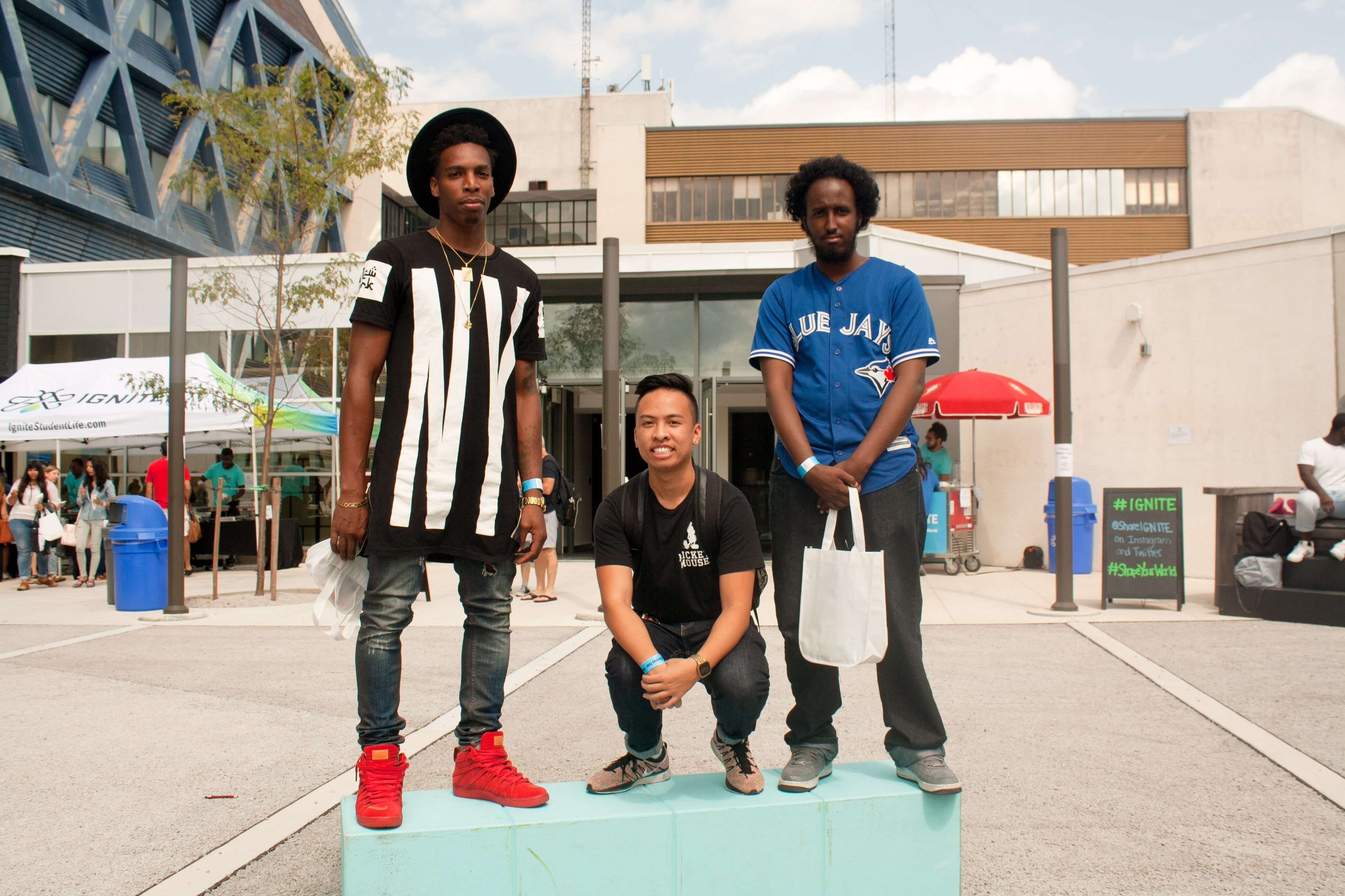 Chris in Red Shoes and Black Fedora, Mark Crouching in Black T-Shirt Beige Sneakers, Dhaha in Blue Jays Jersey