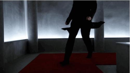 Brett Dalton turning a corner and walking down the hallway in all black suit
