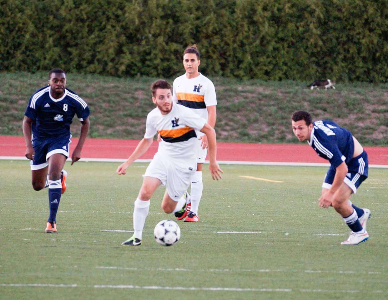 Four soccer players racing for the ball on field