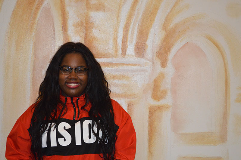 Avery smiling in front of a mural