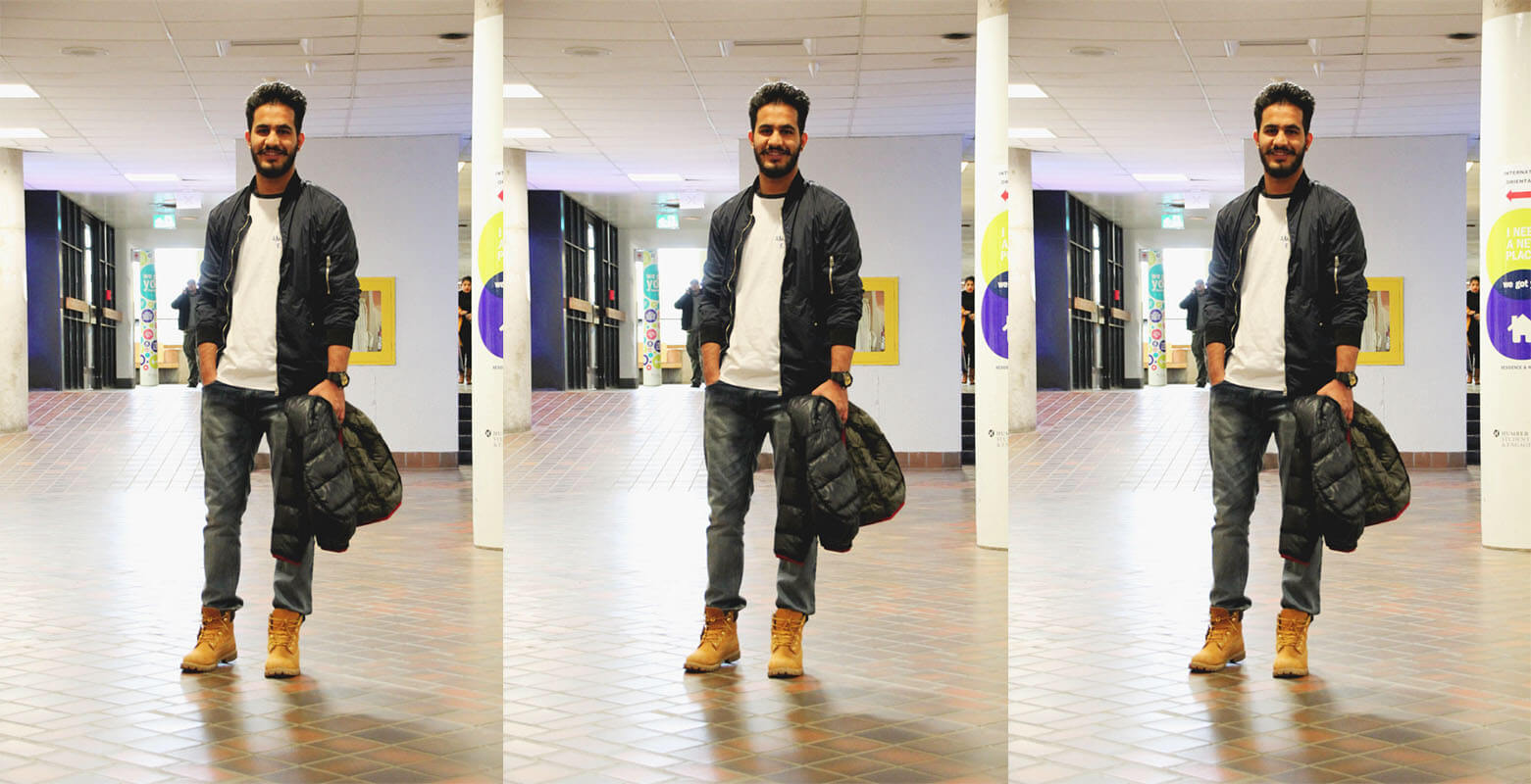 man with beard with one hand in his jean pocket and the other holding his jacket