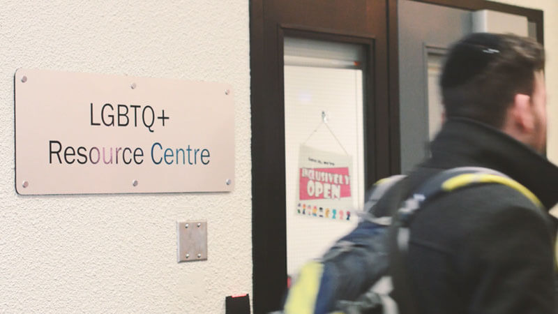 A photo of the doors to Humber College's LGBTQ+ Resource Center, which features a sign that reads "Inclusively Open"
