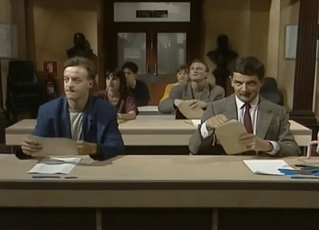 Mr.Bean looks at his paper with one eye covered