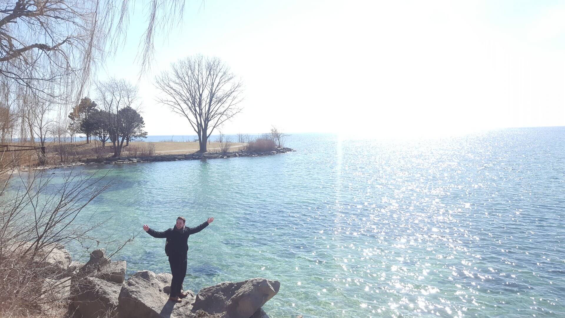man standing in front of a lake with his arms out