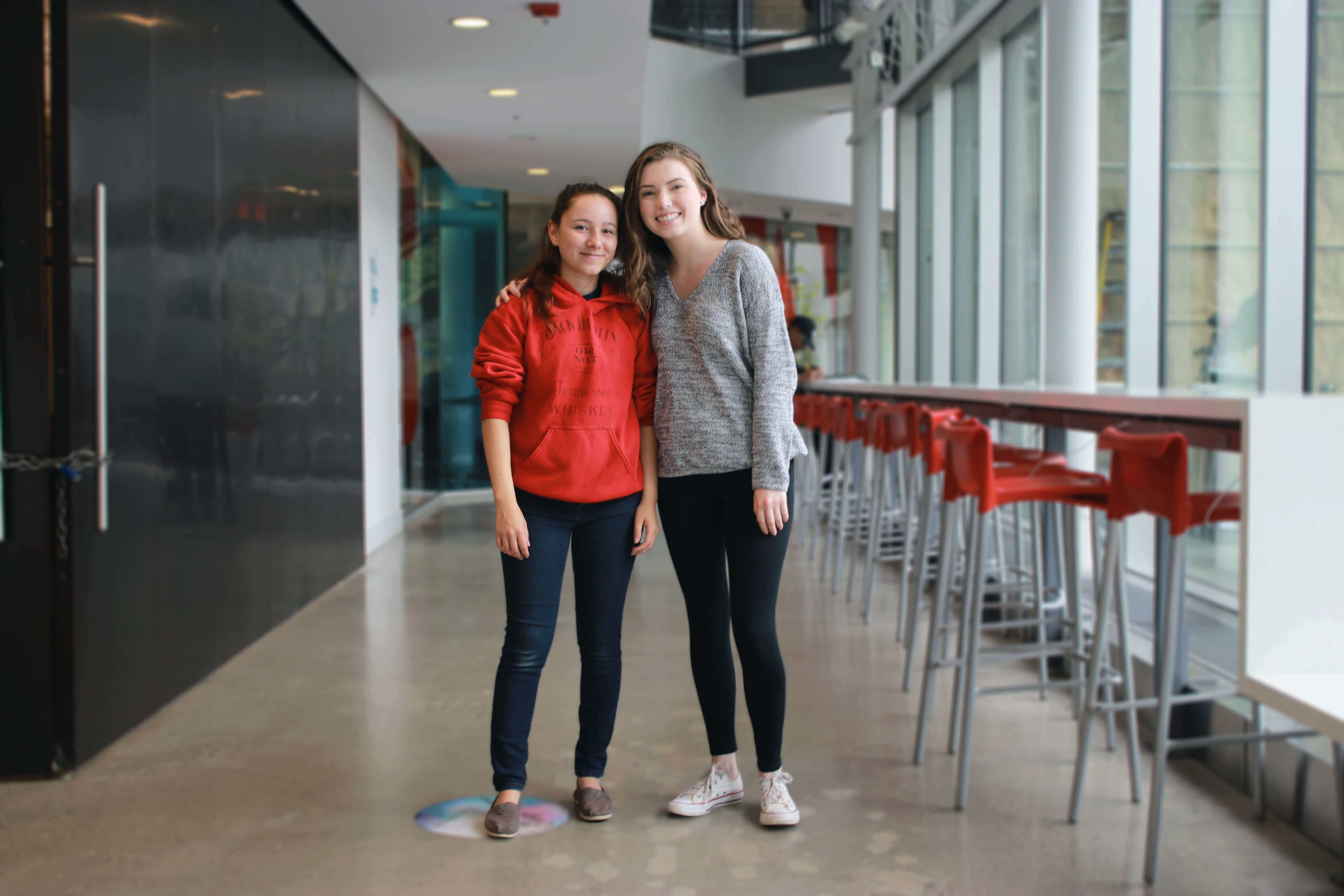 Two girls in sweaters and jeans smiling