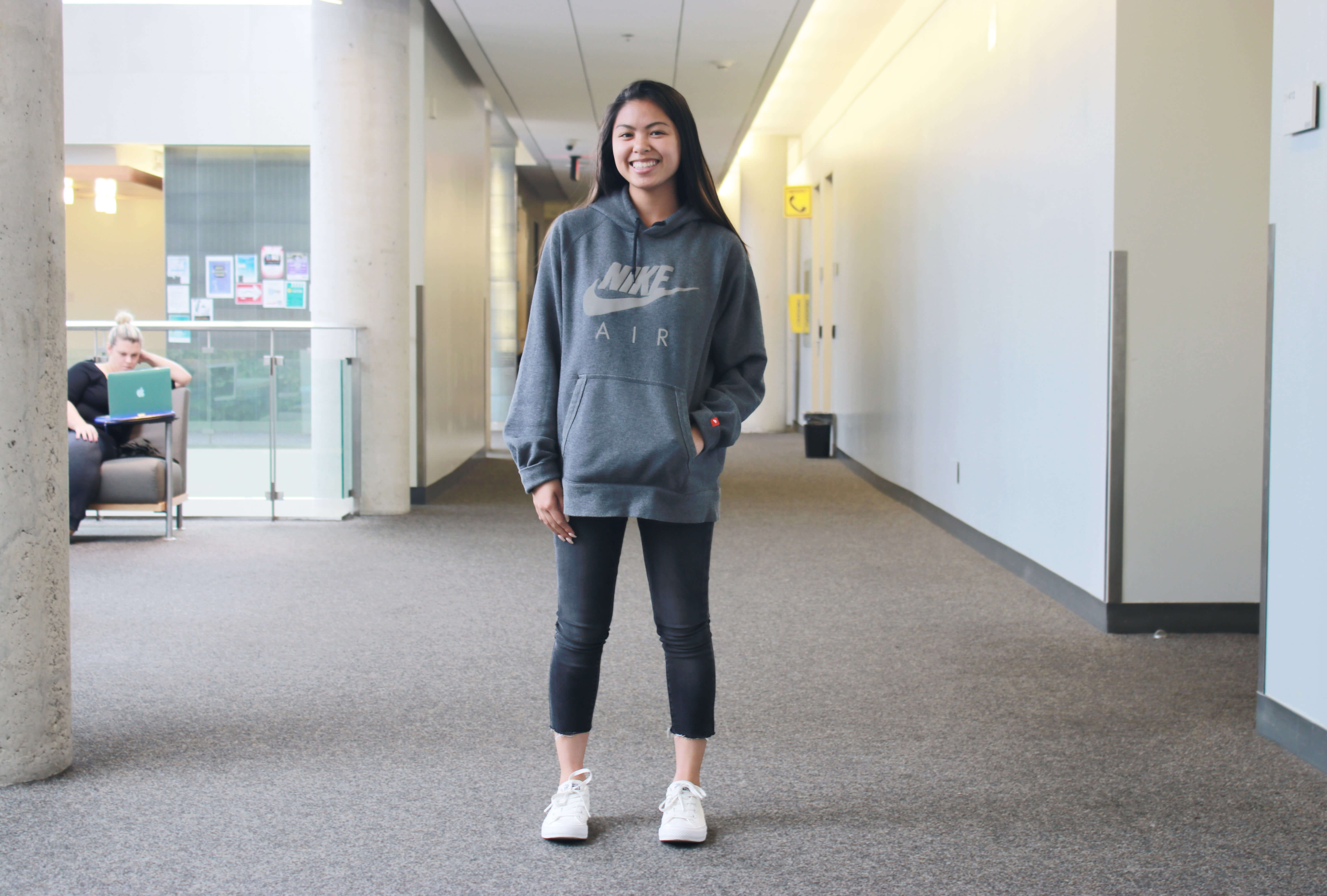 Girl standing in hallway wearing sweater and jeans smiling