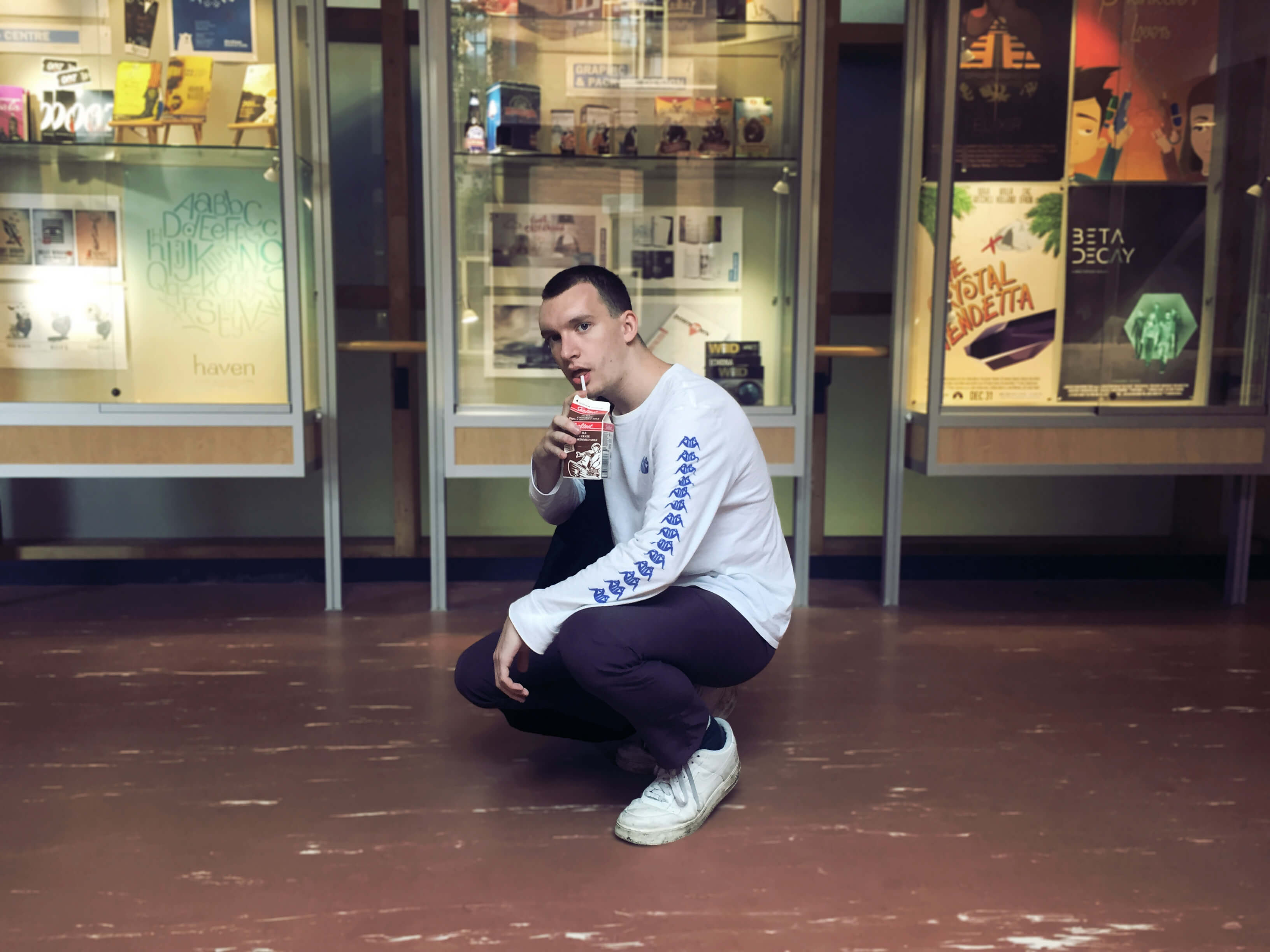 Guy posing for photo wearing sneakers, a pullover and pants drinking chocolate milk