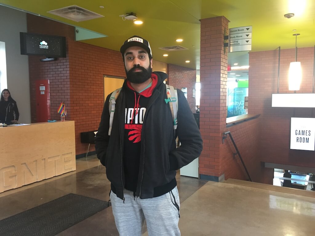 Man wearing raptors sweater, hat and grey track pants.