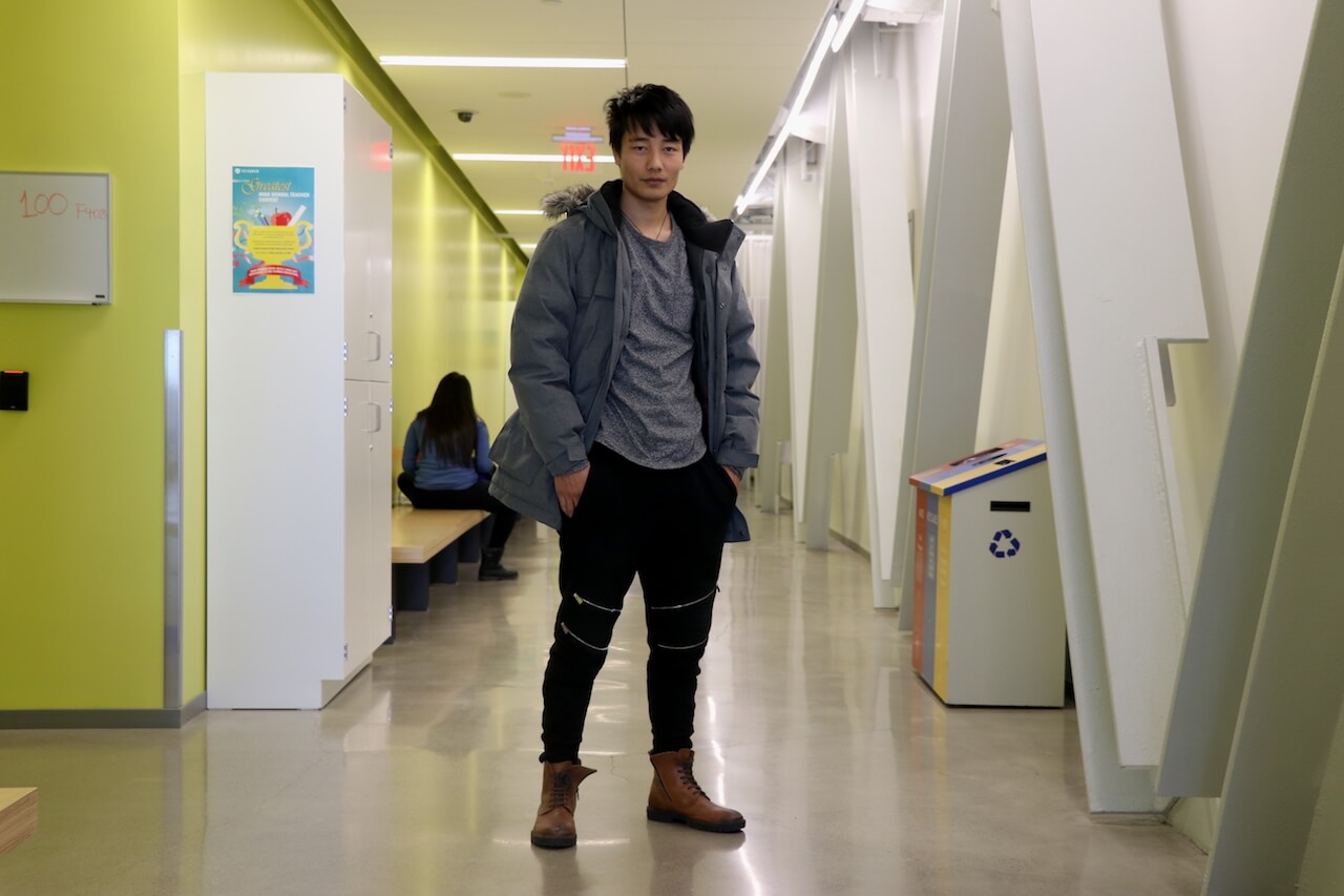 Man poses wearing a winter jacket, jeans, and boots.
