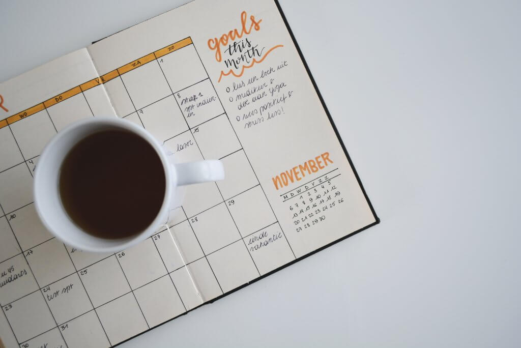 Coffee on top of an open agenda on a white table 