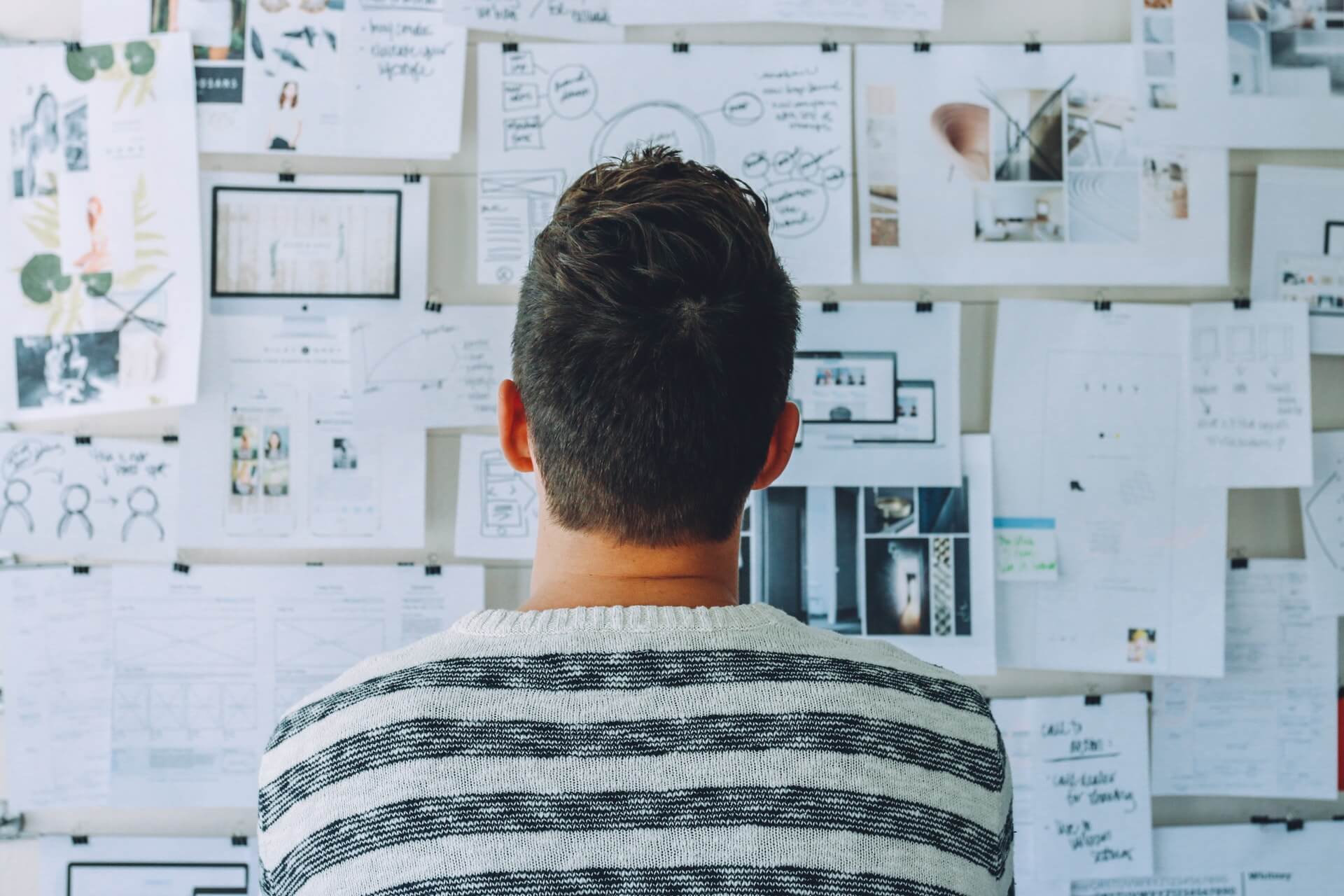 Guy looks at wall with work on it