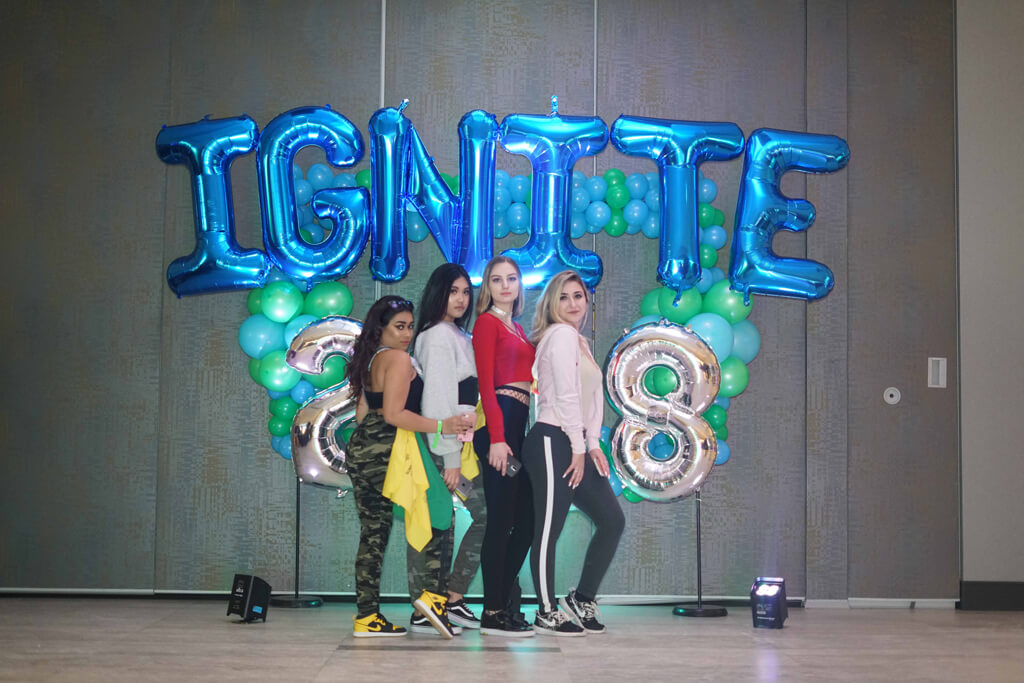 Group of girls pose in front of IGNITE balloons