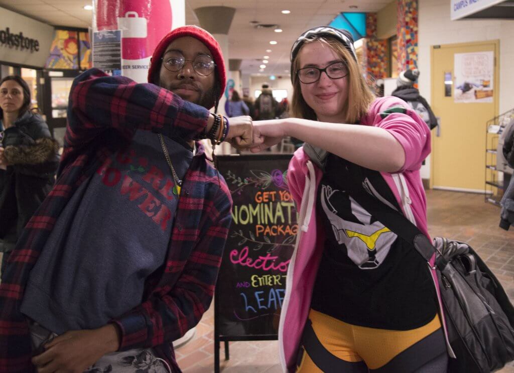 Humber North students Jason and Dana fist-bumping in the hallway