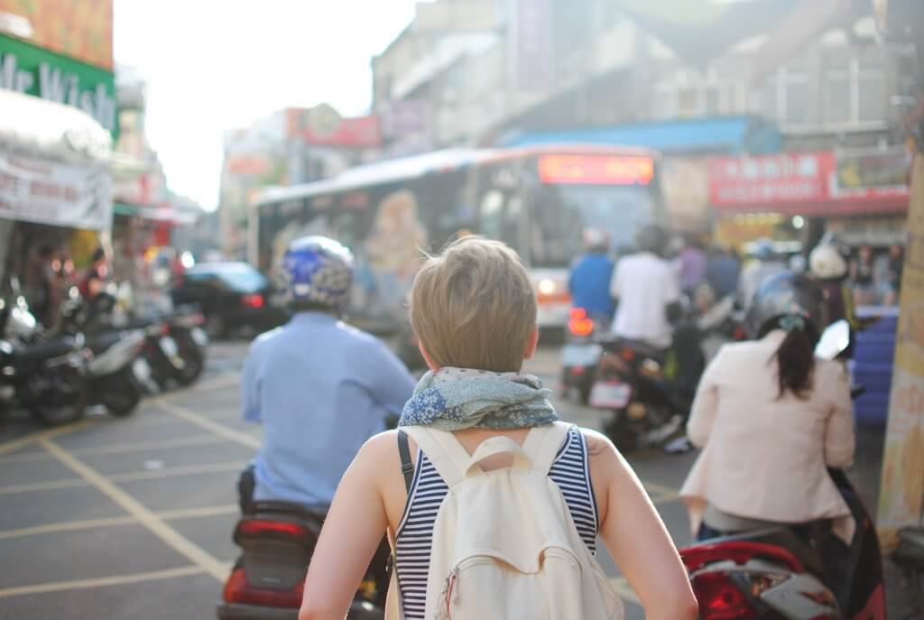 Girl wanders through busy street with a backpack