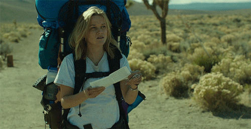 A lady with a map in the middle of the dessert, looking lost.