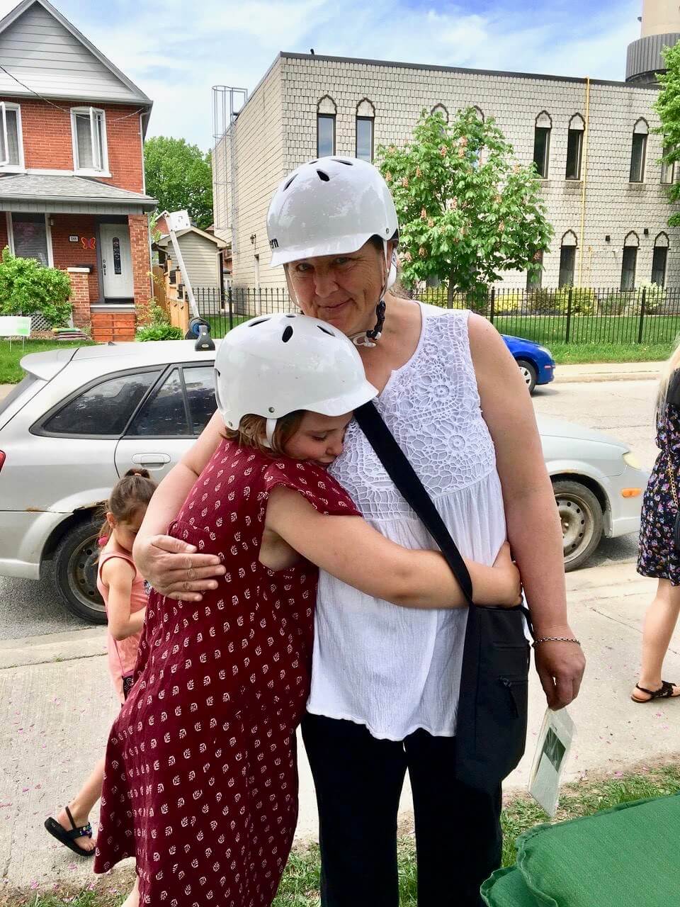 woman wearing a helmet hugging young child wearing a helmet