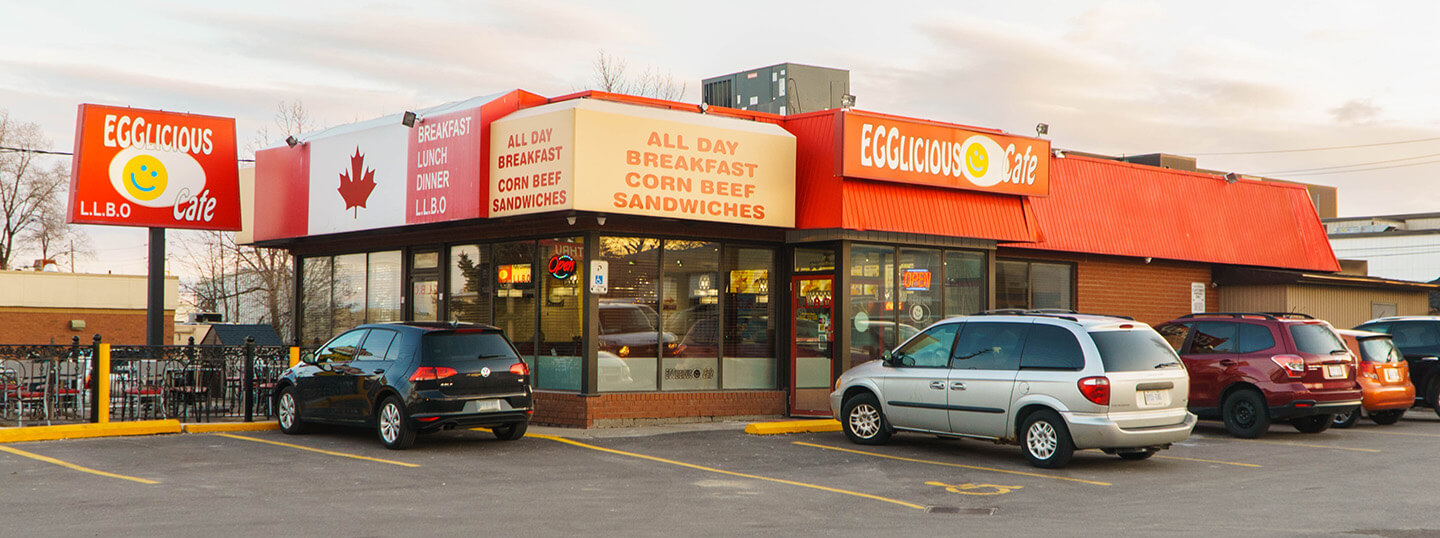 View of storefront and parking lot of Egglicious restaurant on Kipling.