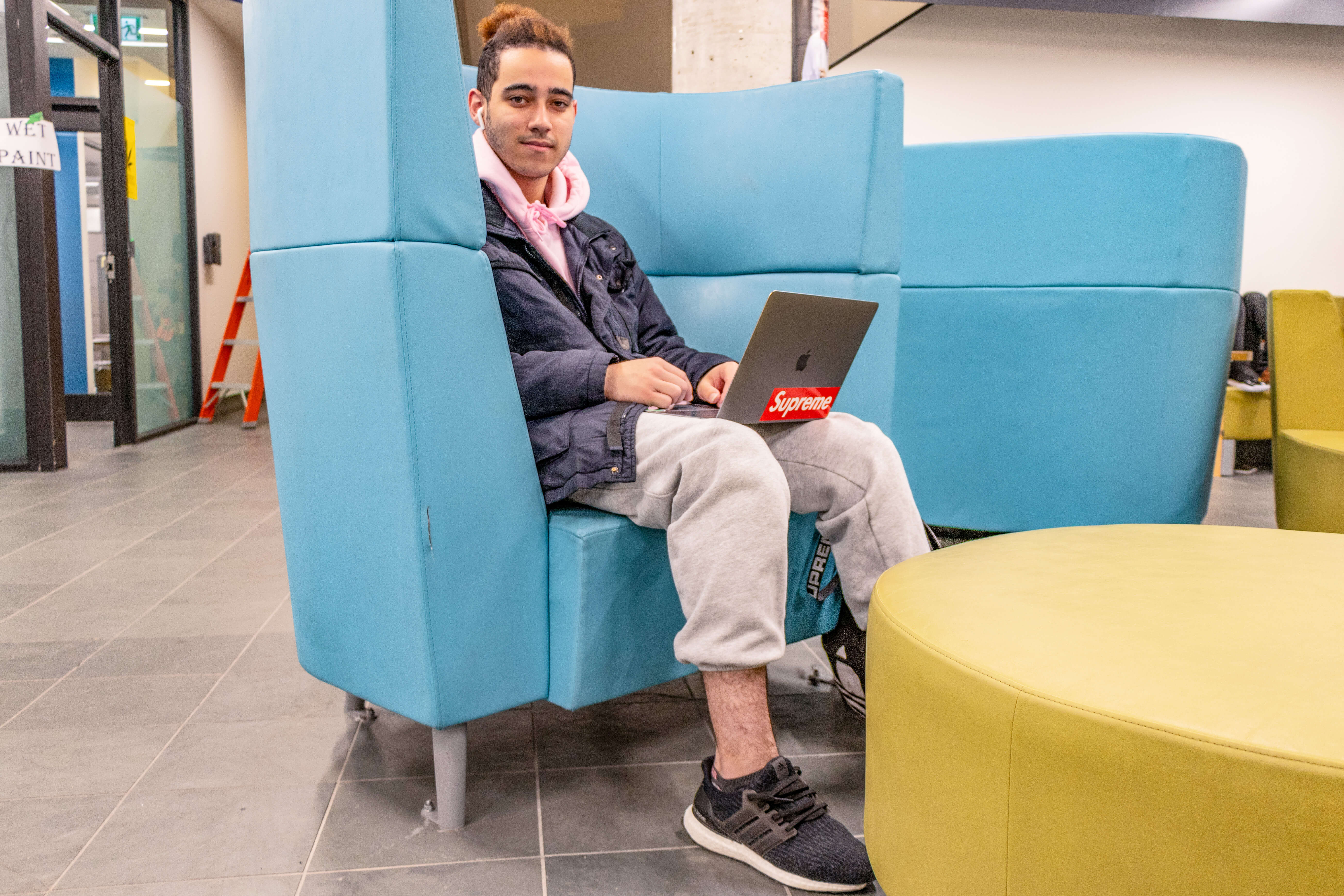 Student in big chair on laptop looks at camera
