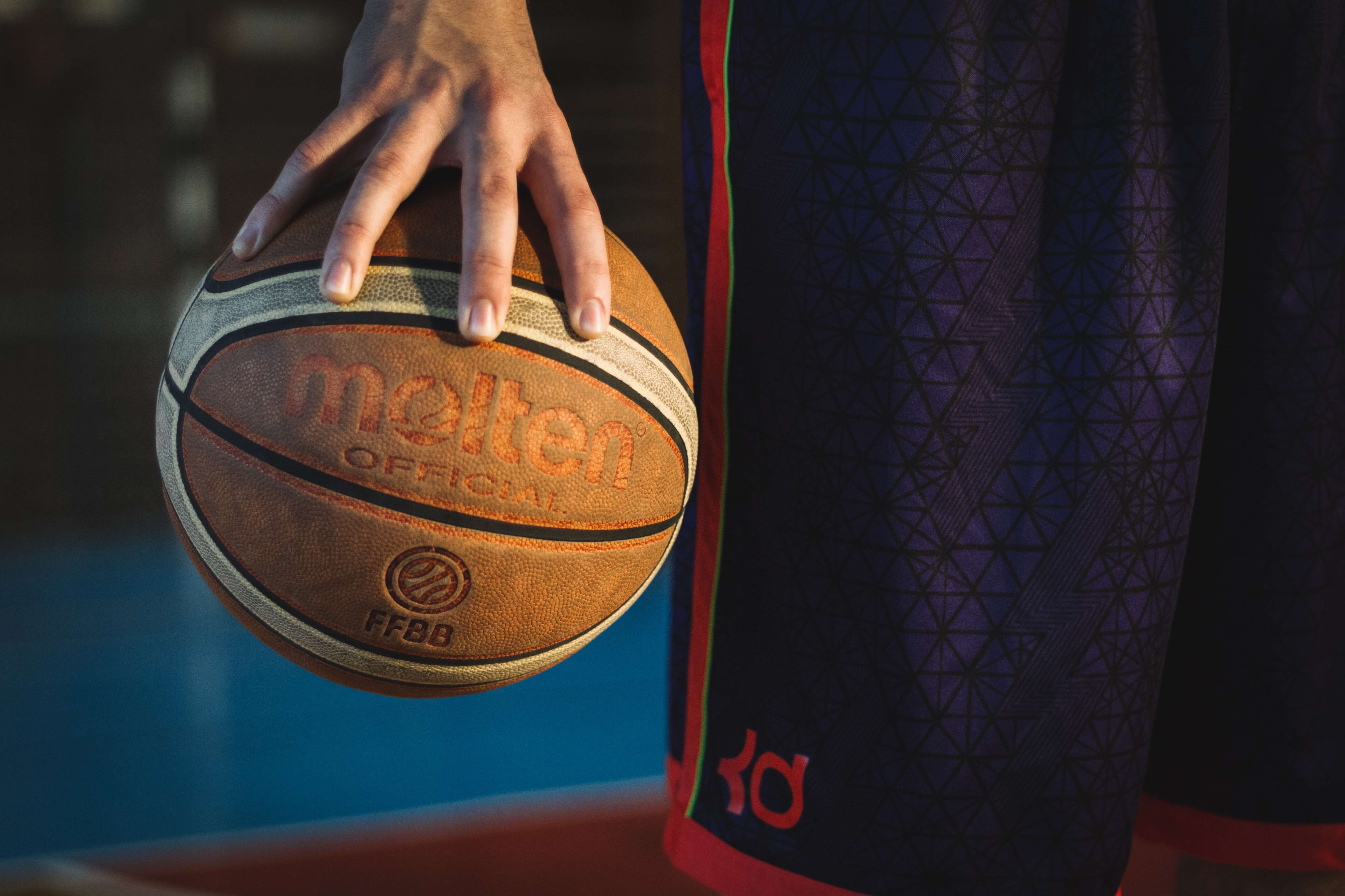 Close up of a man's hand holding a basketball.