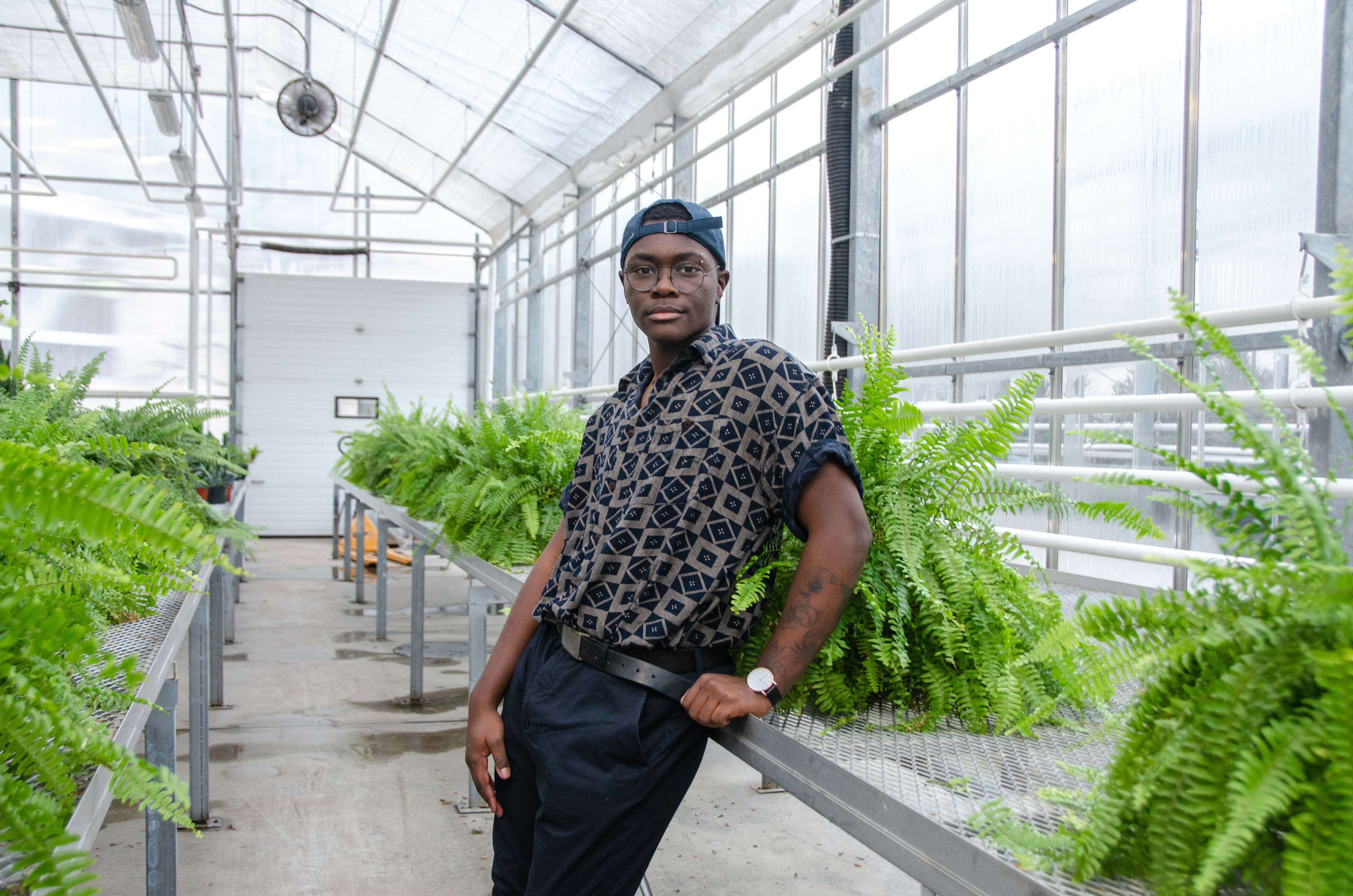 Kristopher Phillips, a member of the LGBTQ community, poses in greenhouse