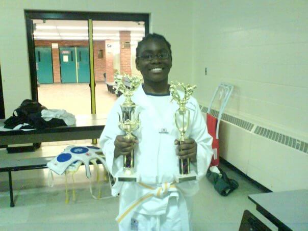 Student Kris Phillips poses with Karate trophies 