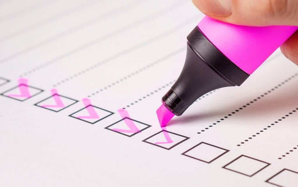person checking boxes on a list with a highlighter