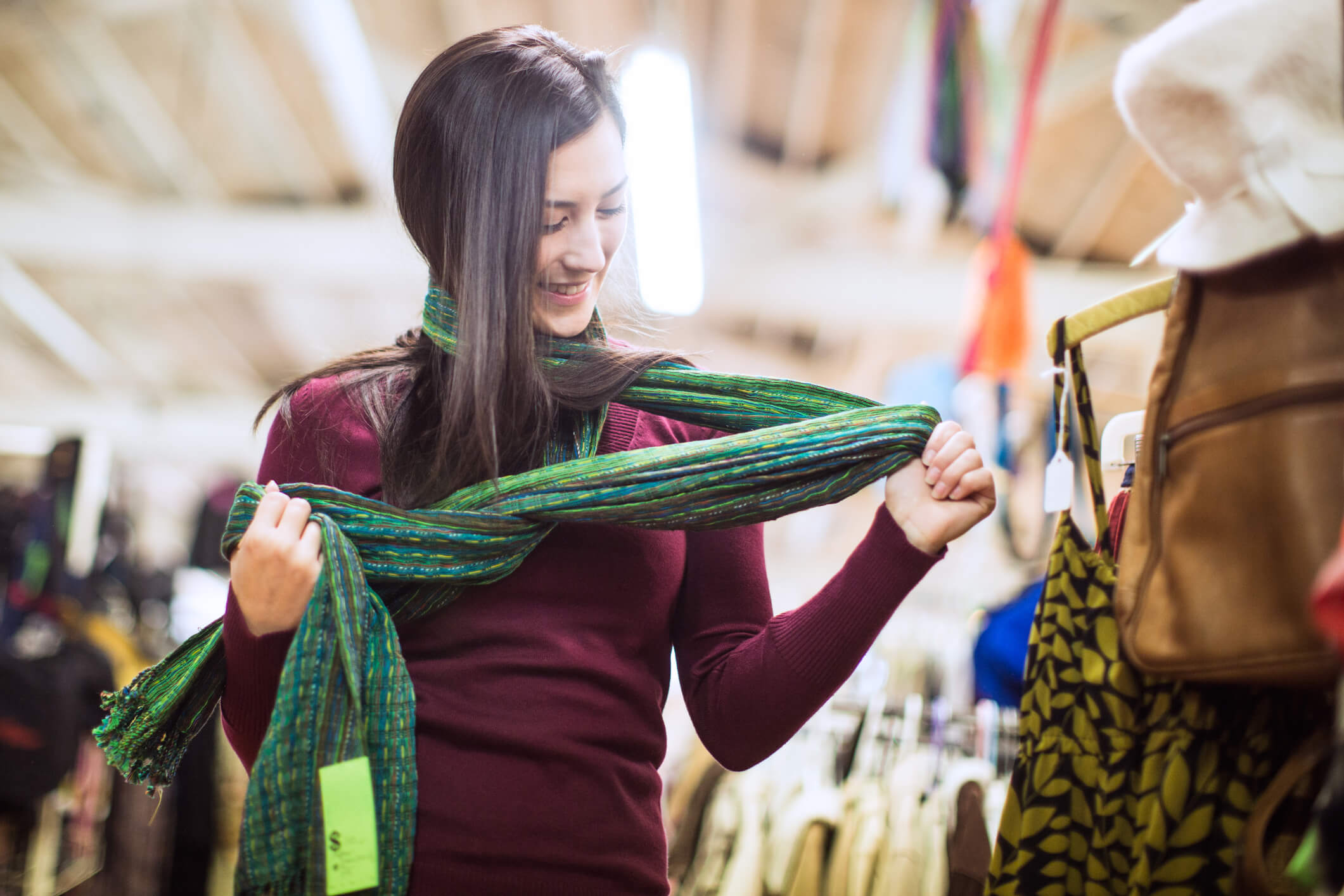 girl wearing scarf looking down at it, smiling.