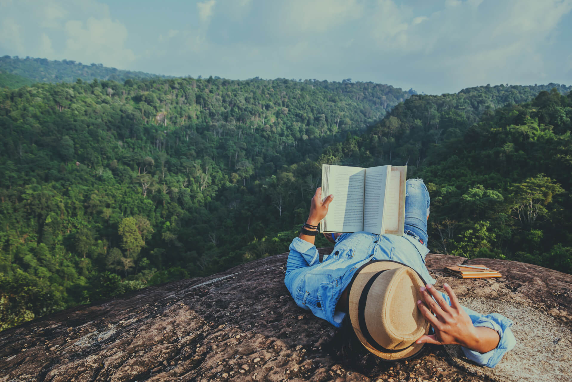 Man laying on mountain reading book