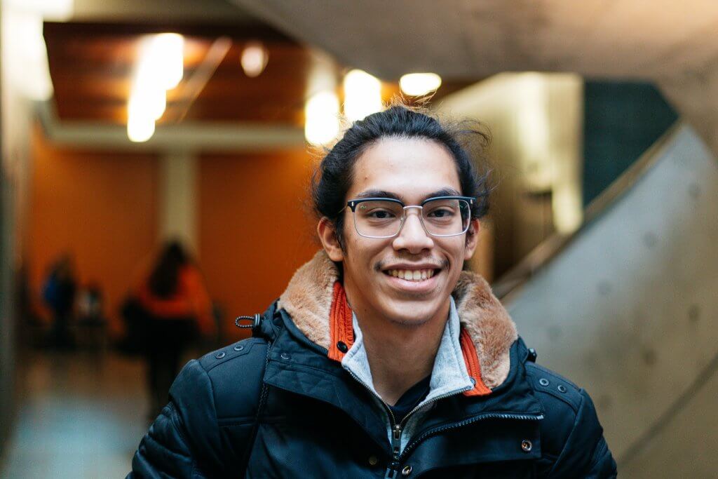 man smiling wearing glasses and jacket.