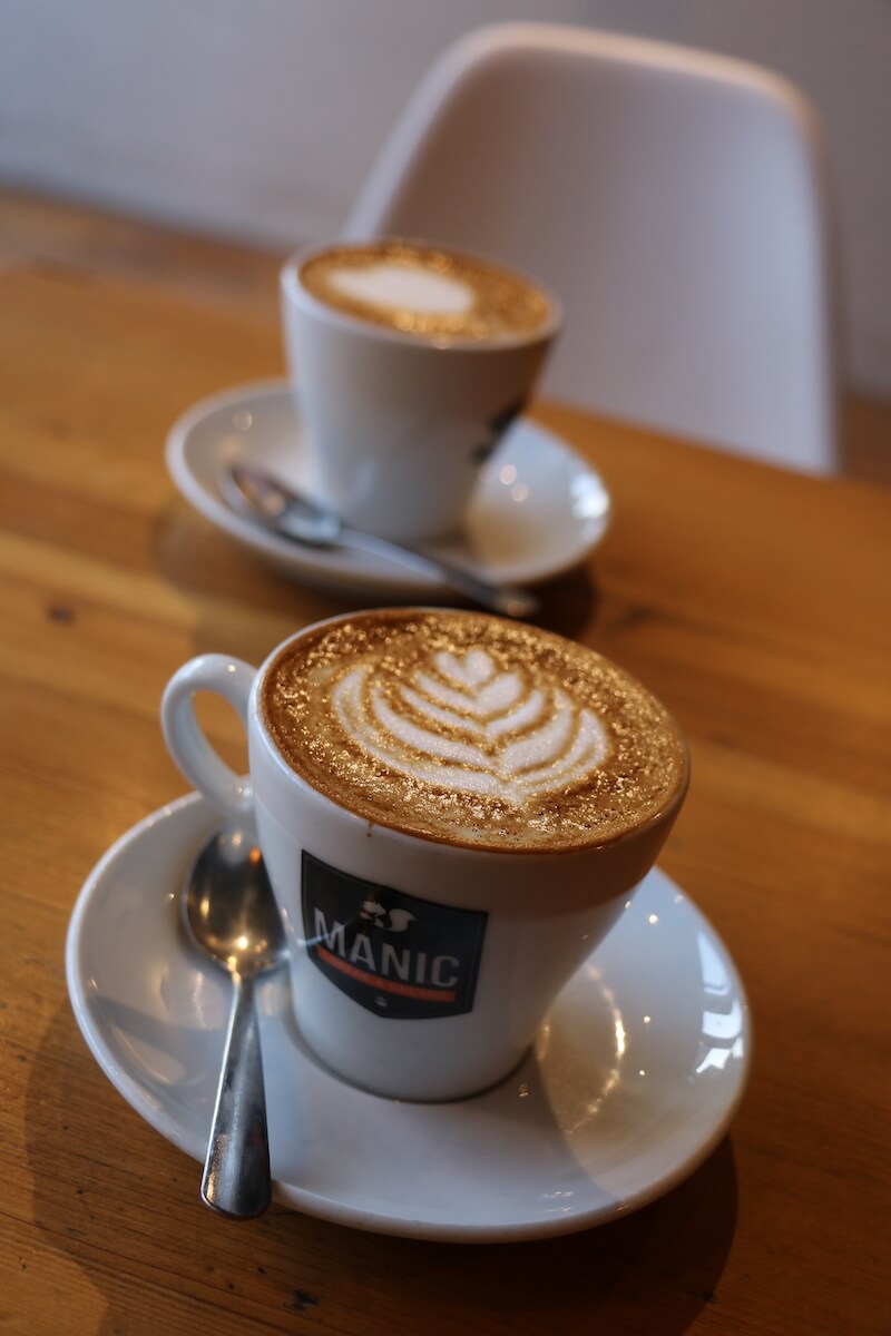 2 cappuccinos in cup reading "Manic Coffee"