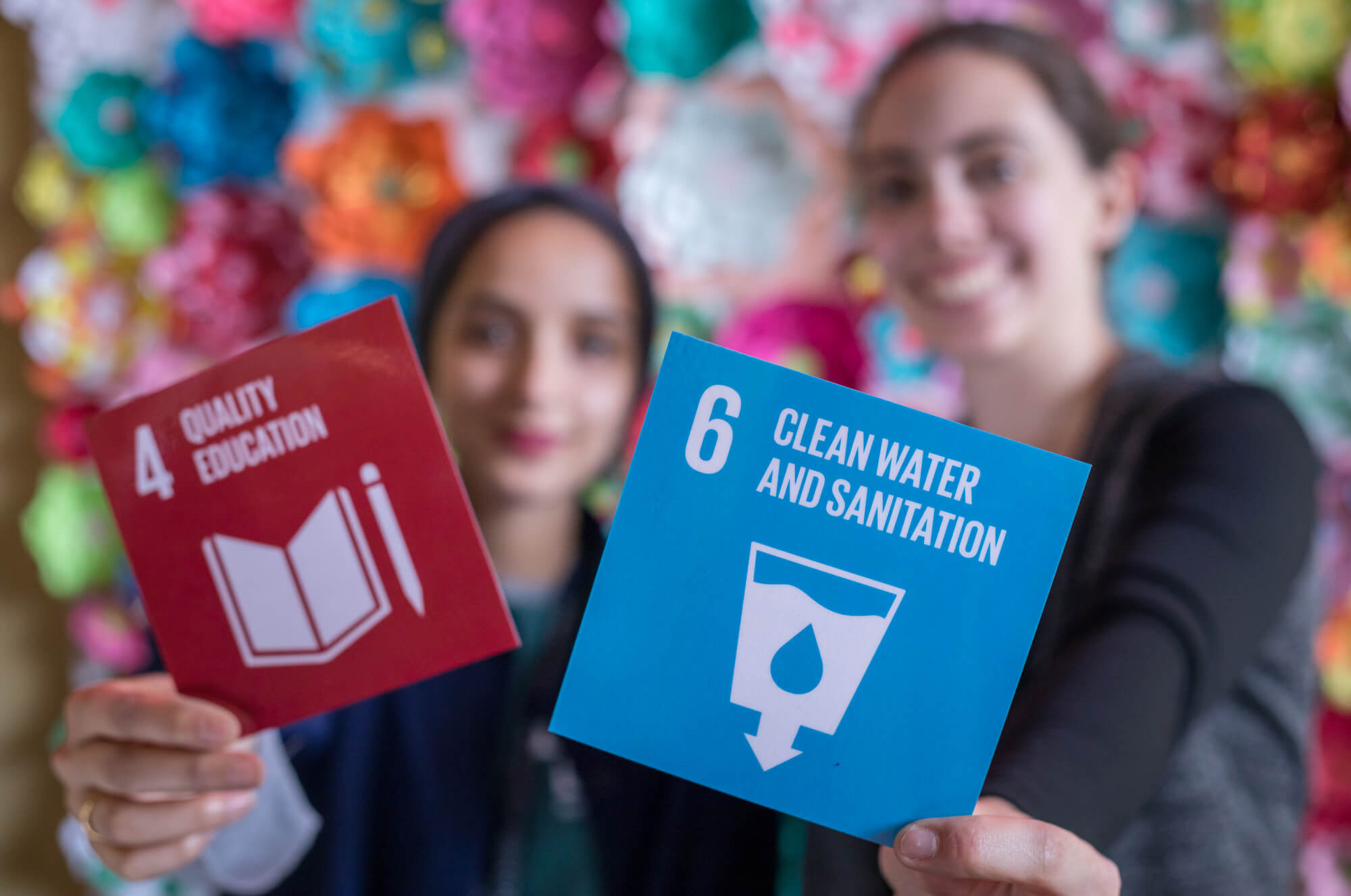 Girls holding up UN pillars of sustainability cards