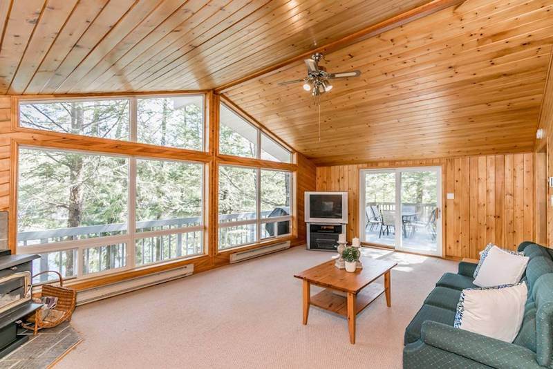Wooden cottage interior with large window showcasing outside view