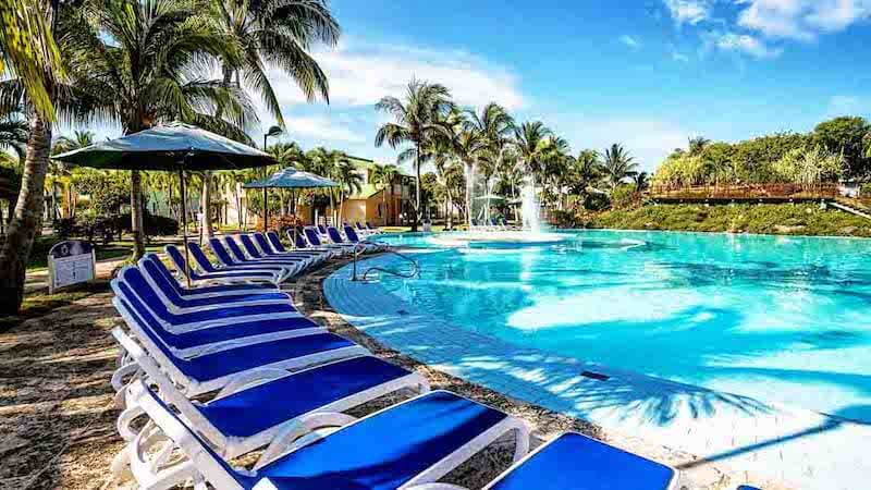 Palm trees next to pool and beach chairs in Cuba