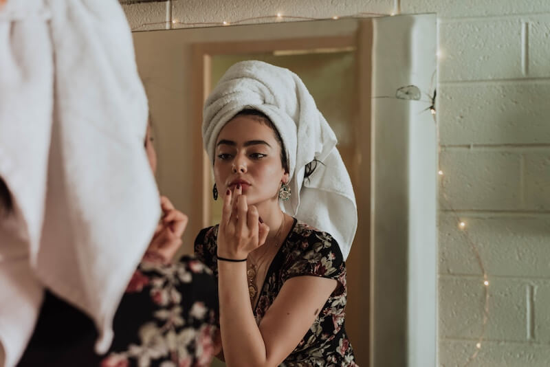 girl wearing towel on hair, putting lip balm on