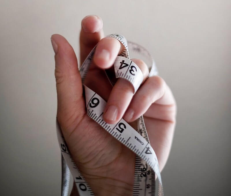 Hand holding white measuring tape