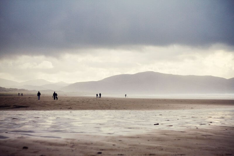 People standing on sand with cloudy sky in background