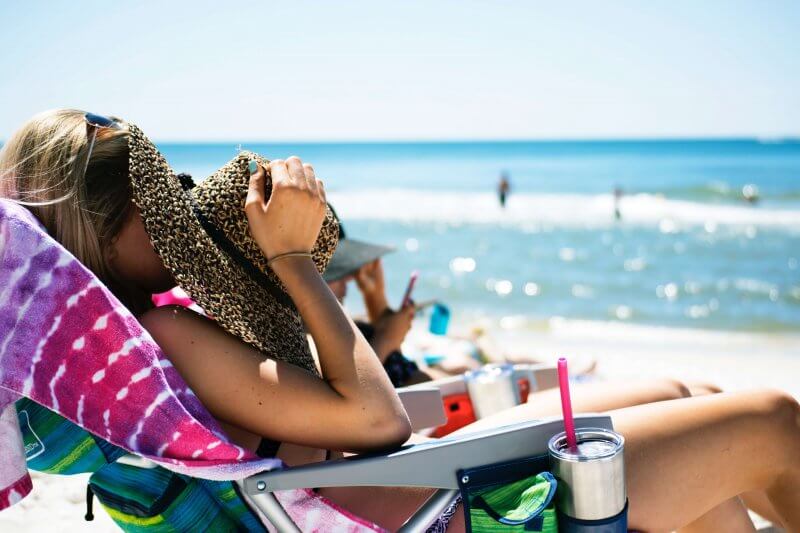 Girl lying down on beach chair with straw hat covering face