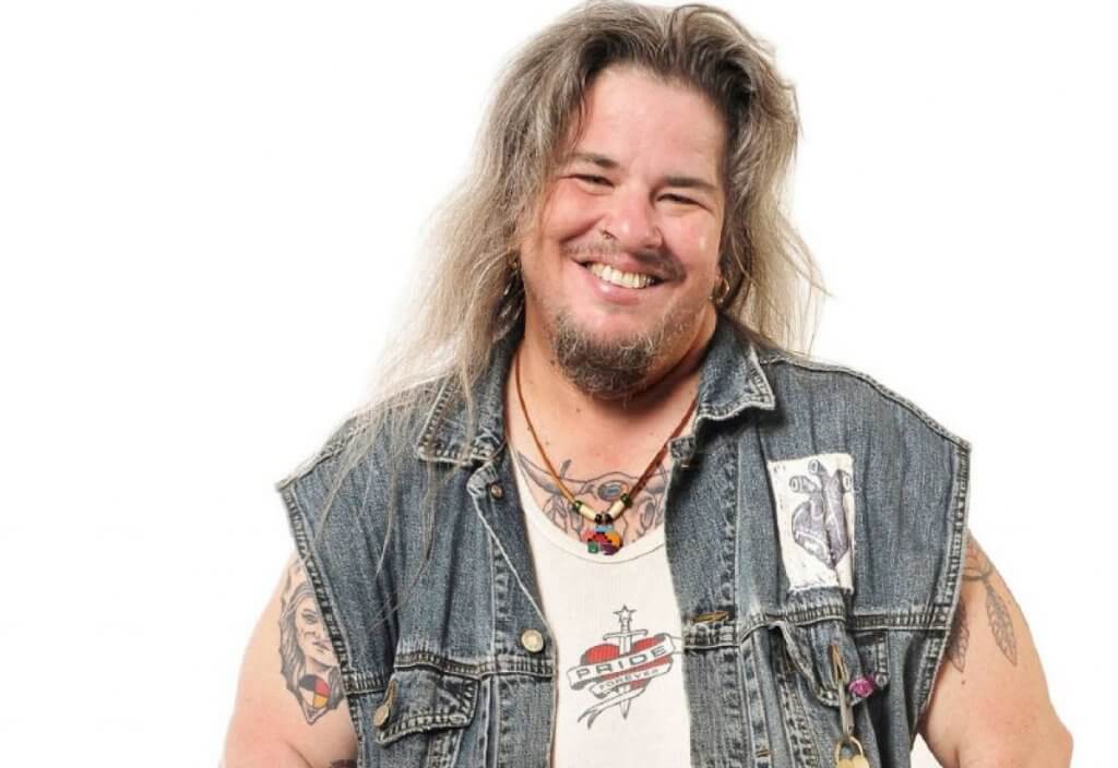 Alec Butler on white backdrop wearing denim vest.