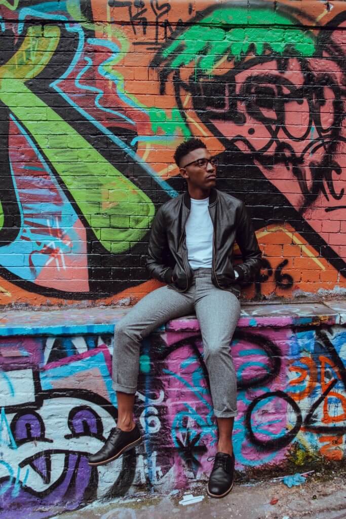 Man sitting in front of graffiti.
