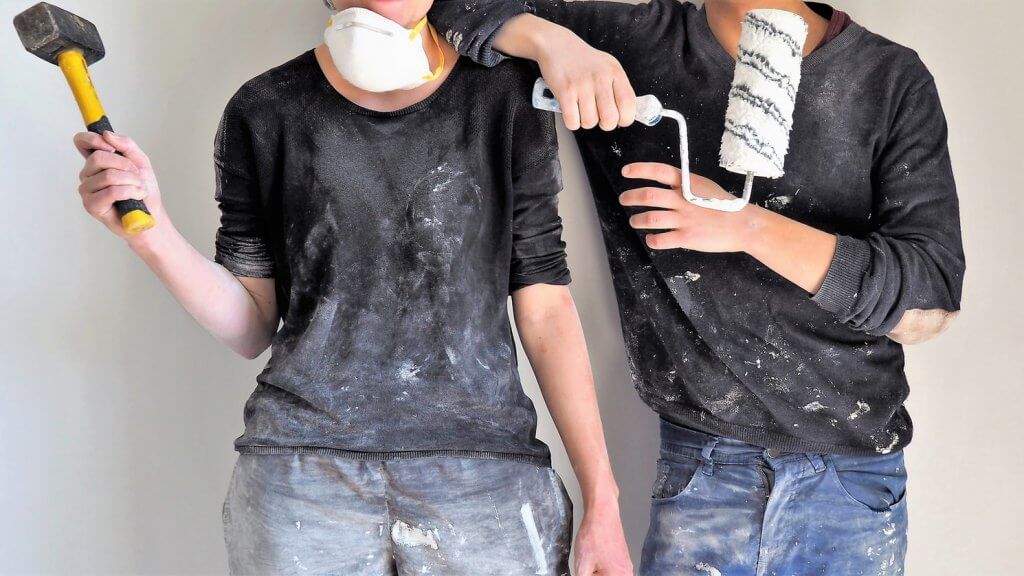 Man and woman holding painting equipment.