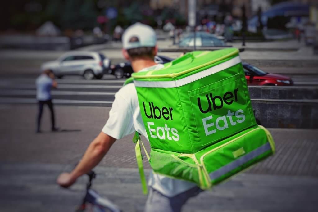 Delivery man on bike with UberEats backpack.