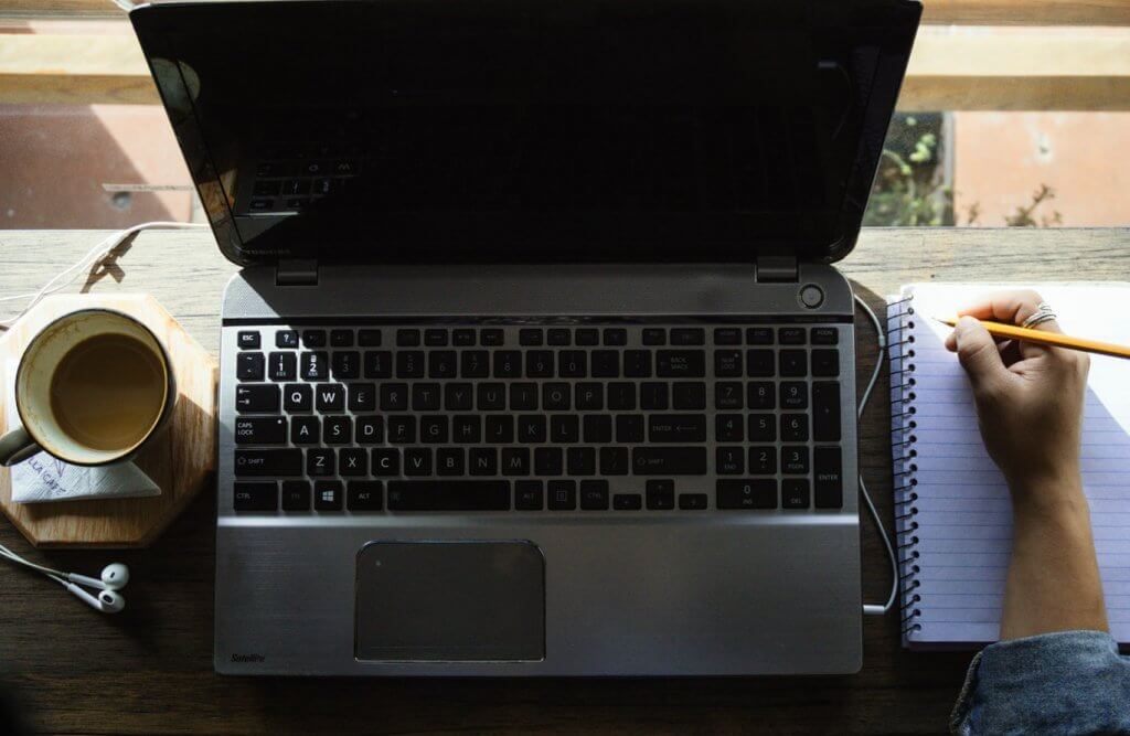 Laptop on desk with coffee and smartphone.