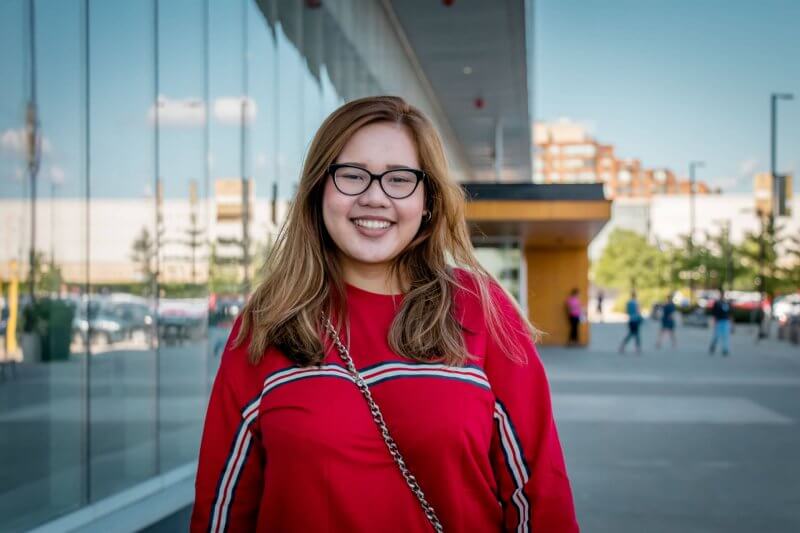 outside picture of girl wearing red shirt and glasses in front of humber college