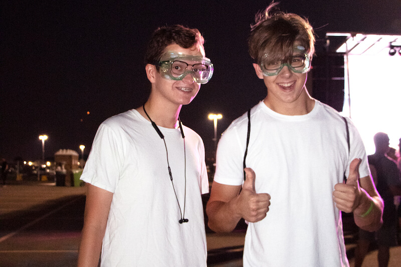2 guys smiling in parking lot, one holding thumbs up