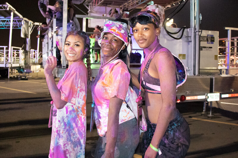 3 girls covered in paint smiling in parking lot
