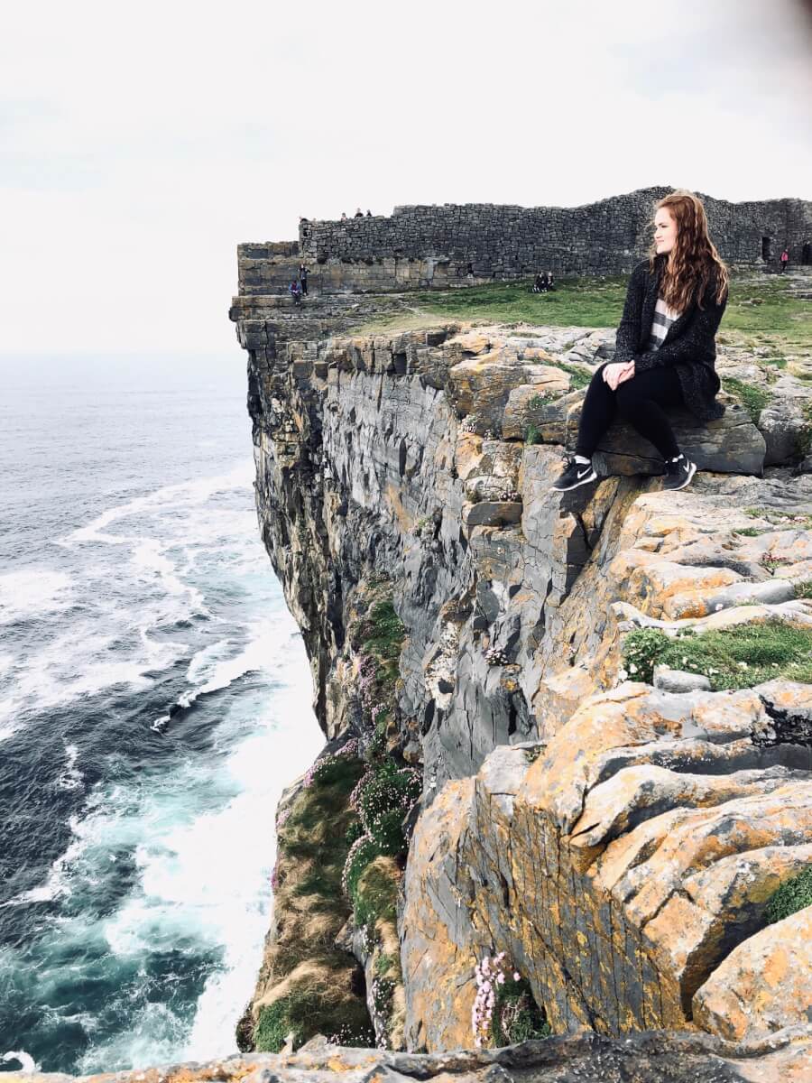 Maegan sitting on the edge of a steep clif