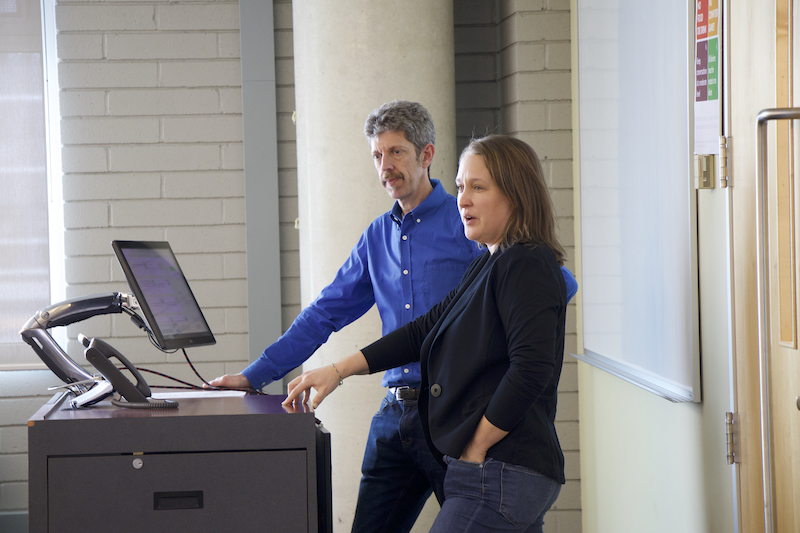 man and woman speaking in front of computer