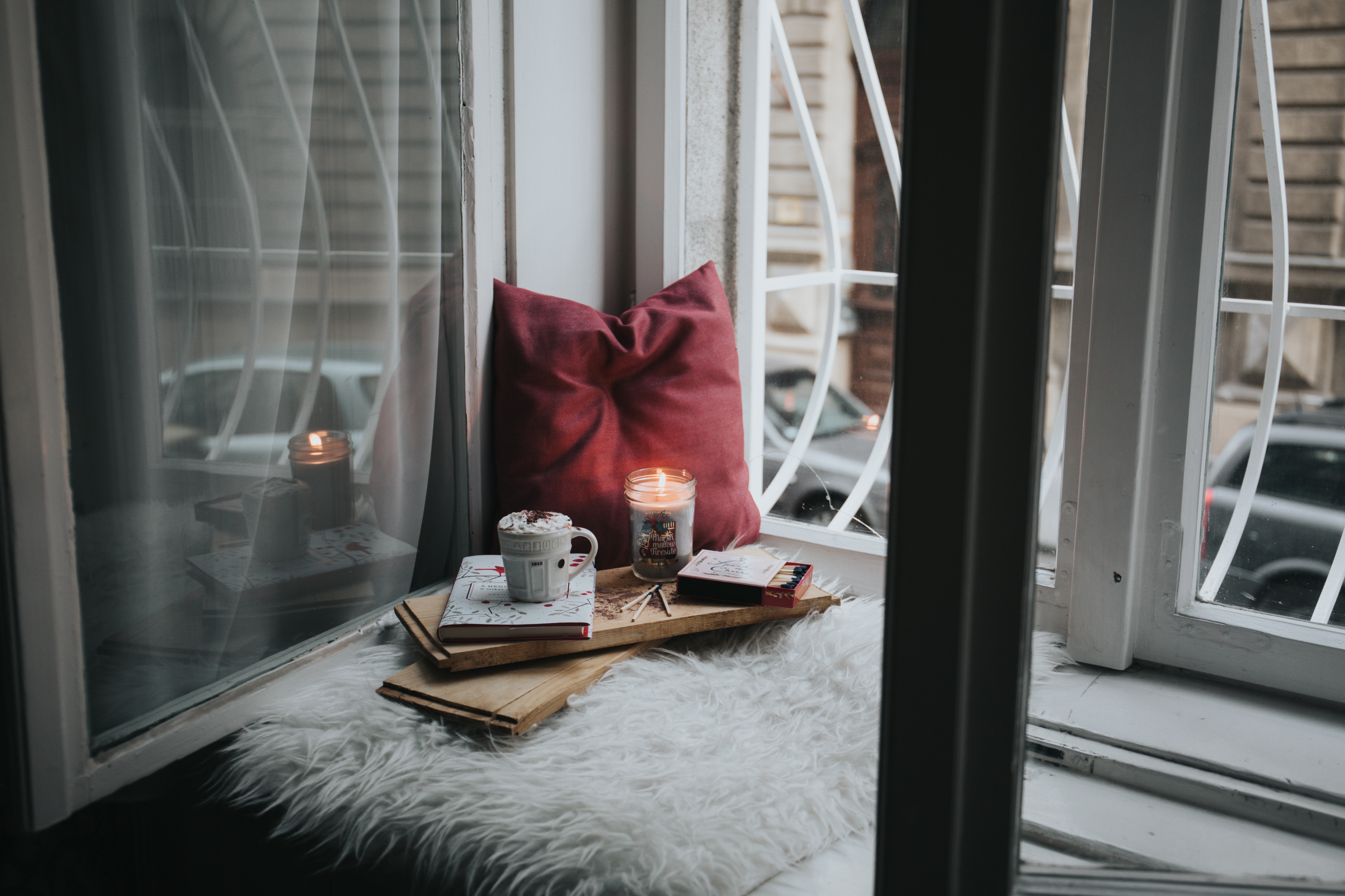 a lit candle, coffee mug, notebook and pillow on a wooden board